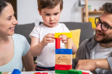 Evde oyuncak tahta bloklarla oynayan genç bir aile.