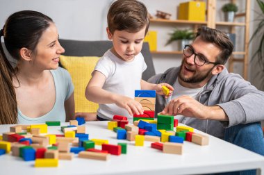 Evde oyuncak tahta bloklarla oynayan genç bir aile.