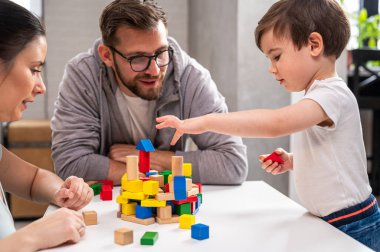 Evde oyuncak tahta bloklarla oynayan genç bir aile.