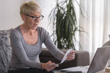 Evde bilgisayar başında çalışan yaşlı, emekli bir kadın aylık giderleri hesaplıyor, ipotek ödemelerini yapıyor, ev bütçesi yapıyor.