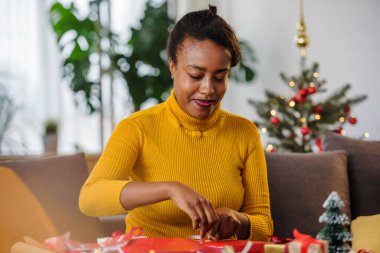 Afro-Amerikan kadın tatillere hazırlanıyor, hediyeleri paketliyor.
