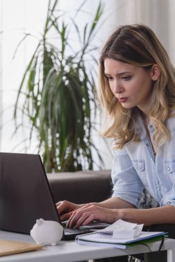 Evde dizüstü bilgisayarla çalışan genç bir kadın. 