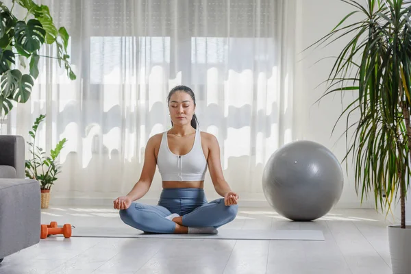 stock image Young Asian woman practicing yoga exercise at home. Daily sports routines for a healthy lifestyle and stress relief.