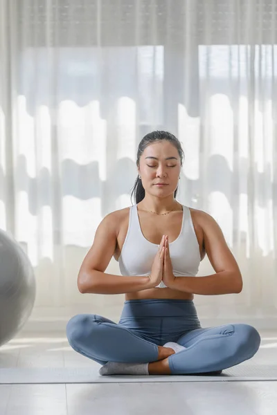 stock image Young Asian woman practicing yoga exercise at home. Daily sports routines for a healthy lifestyle and stress relief.