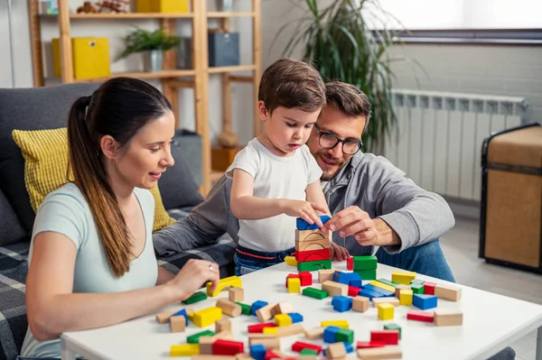 stock image young family playing with toy wooden blocks at home