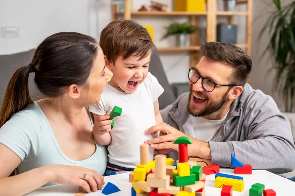 stock image young family playing with toy wooden blocks at home