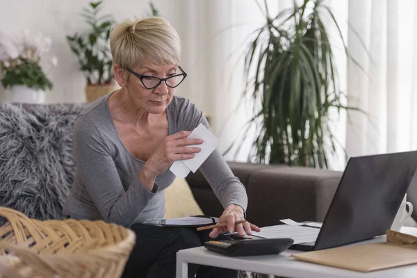 高齢者の退職者の女性は自宅でコンピュータに取り組んで 毎月の費用 住宅ローンの支払いを計算し 住宅予算を行う — ストック写真