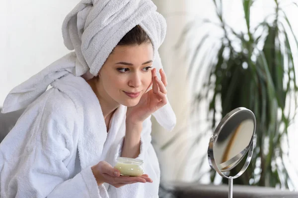 漂亮的年轻女人穿着浴衣和毛巾 看着镜子 护肤的概念 — 图库照片