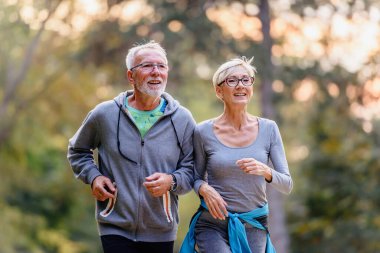 Yaşlı çift parkta koşuyor. 
