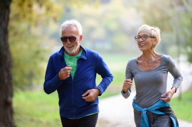 Mutlu yaşlı çift parkta koşuyor.