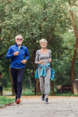 Mutlu yaşlı çift parkta koşuyor.