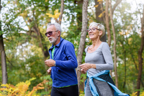 happy senior couple jogging in park