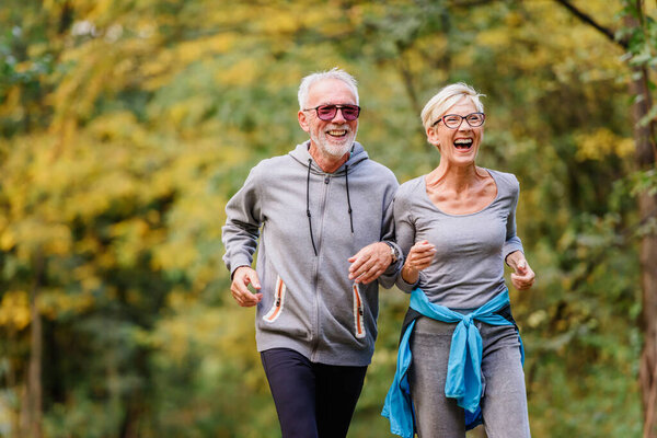 happy senior couple jogging in park