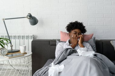 Yatakta grip olan Afrikalı bir kadın.