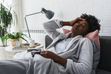 Yatakta grip olan Afrikalı bir kadın.