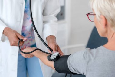 Afrikalı Amerikalı doktor, yaşlı kadın hastayı muayene ediyor.