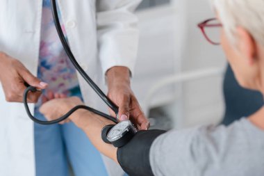 Afrikalı Amerikalı doktor, yaşlı kadın hastayı muayene ediyor.
