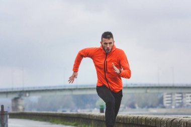 Genç adam şehirde koşuyor. 