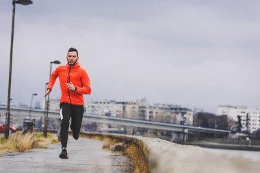 Genç adam şehirde koşuyor. 