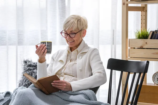 Старша Жінка Читає Книгу Чай Вдома — стокове фото