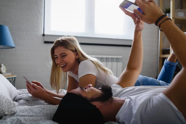 Çift Telefonuyla Yatakta Yatıyor — Stok fotoğraf