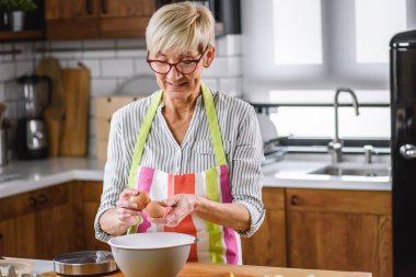 Yaşlı kadın ev mutfağında yemek pişiriyor..