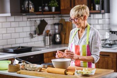 Yaşlı kadın ev mutfağında yemek pişiriyor. Olgun kadın yemekleri.