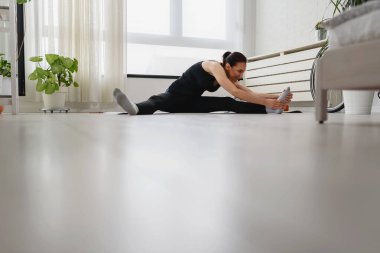 Genç kadın esneme egzersizleri yapıyor. 