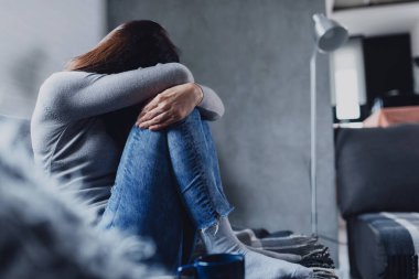Evde yalnız oturan bir kadın depresyonda. Duygusal stres yüzünden. Sosyal Mesafe ve kişisel izolasyon.
