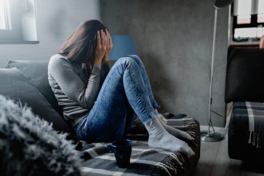 Evde yalnız oturan bir kadın depresyonda. Duygusal stres yüzünden. Sosyal Mesafe ve kişisel izolasyon.