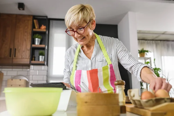 Старша Літня Жінка Випікає Домашній Кухні Використовуючи Планшетний Комп Ютер — стокове фото
