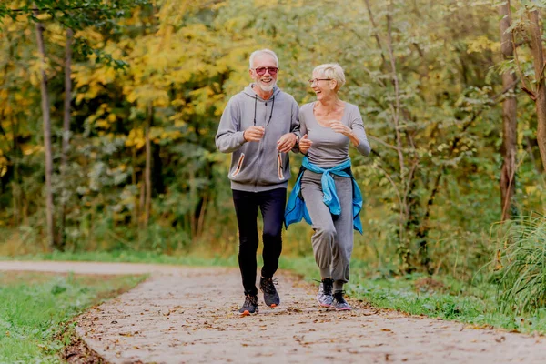 Yaşlı çift parkta koşuyor. 