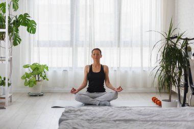 Evde yoga egzersizi yapan genç bir kadın. Sağlıklı bir yaşam tarzı ve stres atma için günlük spor programları.