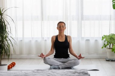 Evde yoga egzersizi yapan genç bir kadın. Sağlıklı bir yaşam tarzı ve stres atma için günlük spor programları.
