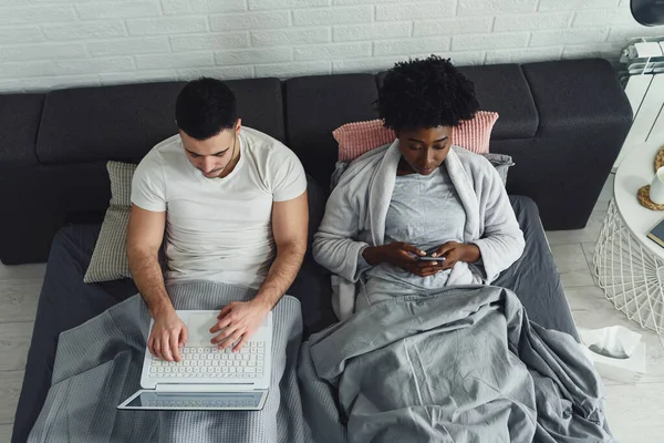 Young Multiracial Couple Using Mobile Electronic Devices Bed Ignoring Each — Stock Photo, Image