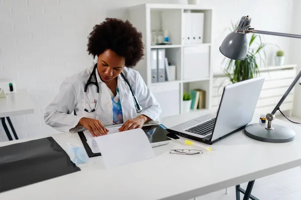 Donna Medico Con Stetoscopio Guardando Documenti Medici Presso Suo Ufficio — Foto Stock