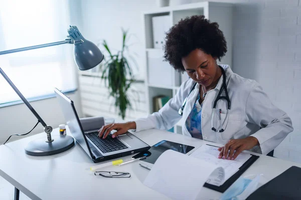 Kobieta Lekarz Pracująca Swoim Biurze Przed Laptopem Pisząca Raport Zdrowotny — Zdjęcie stockowe