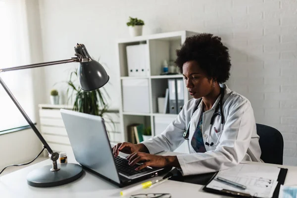 Kobieta Lekarz Pracująca Swoim Biurze Przed Laptopem Pisząca Raport Zdrowotny — Zdjęcie stockowe