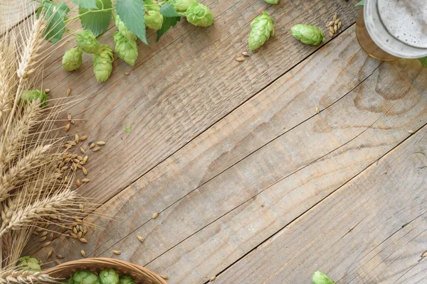 木制背景下的绿色跳跃锥和啤酒杯 — 图库照片