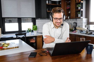 Kulaklıklı genç adam dizüstü bilgisayarla çalışıyor. 