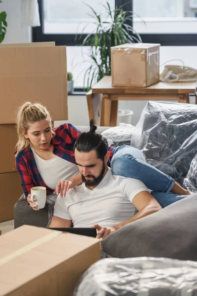 stock image Young couple moving in new home.Sitting on floor and relaxing after unpacking.Looking something on laptop