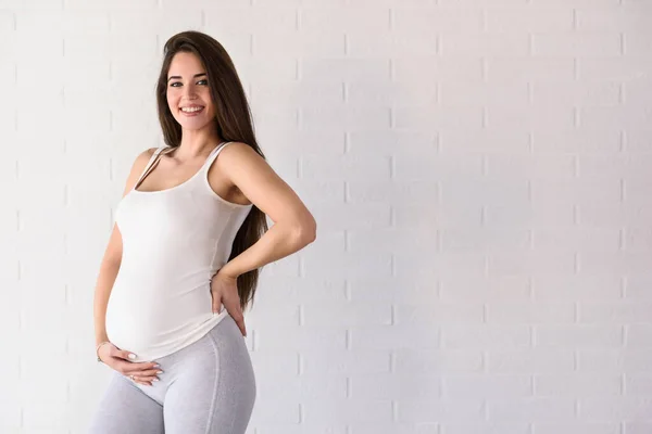 Genç Güzel Hamile Bir Kadın Tuğla Duvarın Üzerinde Duruyor — Stok fotoğraf