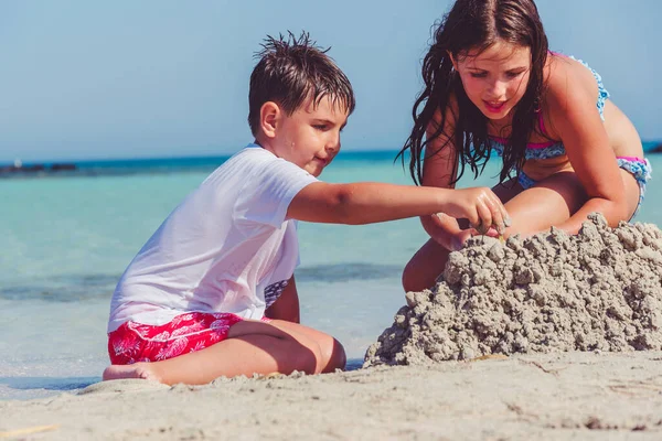 ビーチで砂の城を作る兄と妹 — ストック写真