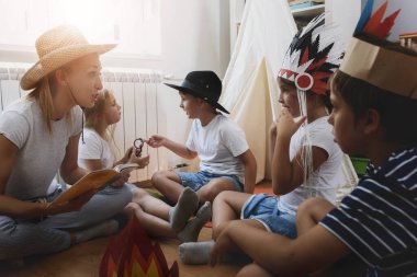 Anaokulunda kitap okuyan öğretmenlerin listesini yapan bir grup çocuk.