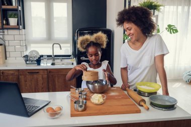 Afro-Amerikan anne ve kızı evde birlikte yemek pişiriyor. 