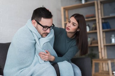 Evdeki kanepede oturan genç ve güzel bir çift. Adam grip olmuş. Mevsimsel hastalık