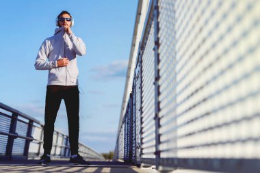 Sokakta cep telefonu ve kulaklığı olan genç bir adam.