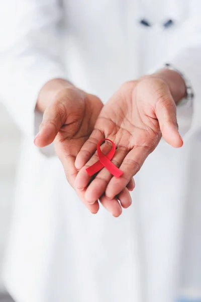 stock image red ribbon, aids awareness. in doctors hands