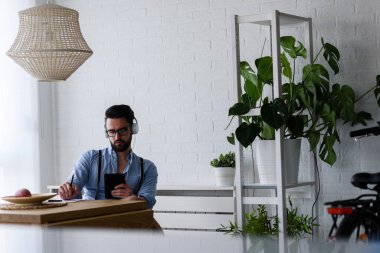 Genç adam evde dizüstü bilgisayar kullanarak çalışıyor. ev ofisi kavramı.