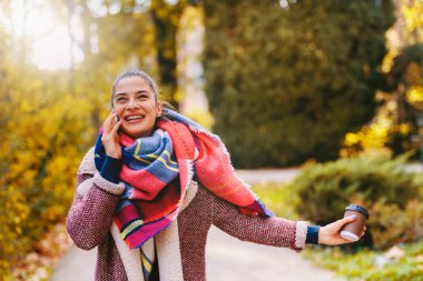 Şehir parkında cep telefonu kullanan gülümseyen kız. 